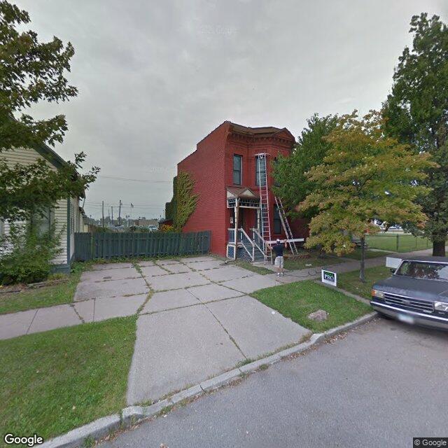 September 2013: a rowhouse under repair, chain-link fence and weeds, the pole above it all.