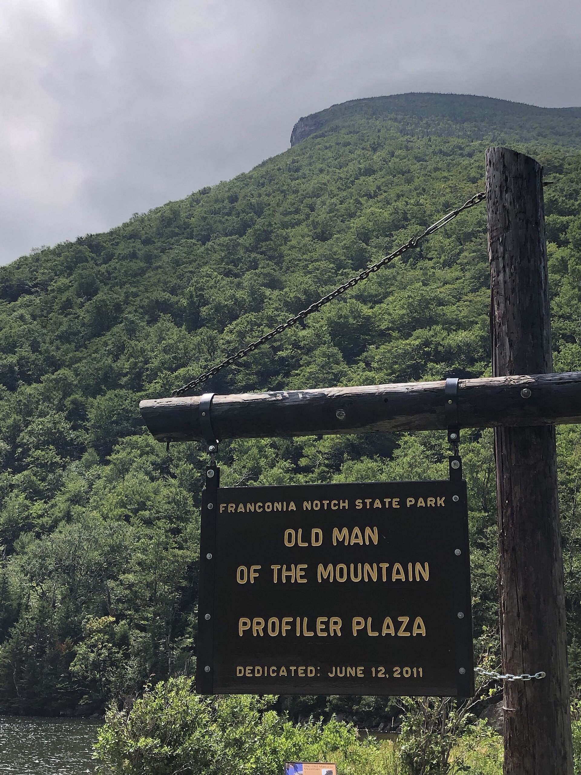 The plaza sign: “FRANCONIA NOTCH STATE PARK / OLD MAN OF THE MOUNTAIN / PROFILER PLAZA / DEDICATED: JUNE 12, 2011”. Photo: Dmoore5556, CC BY-SA 4.0, via Wikimedia Commons.